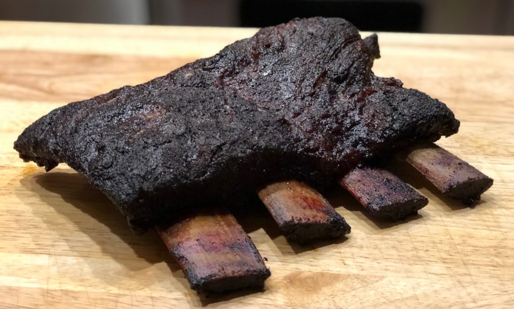 beef short ribs covered in black bark on a cutting board