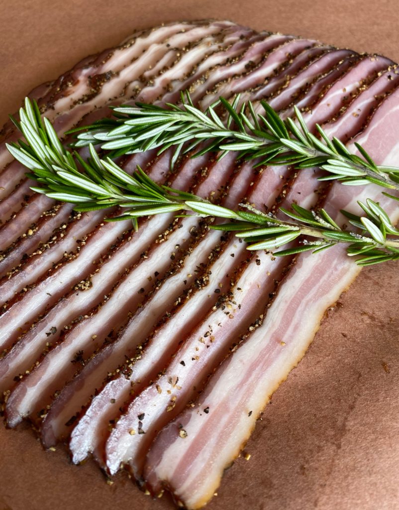 sliced bacon with a sprig of rosemary