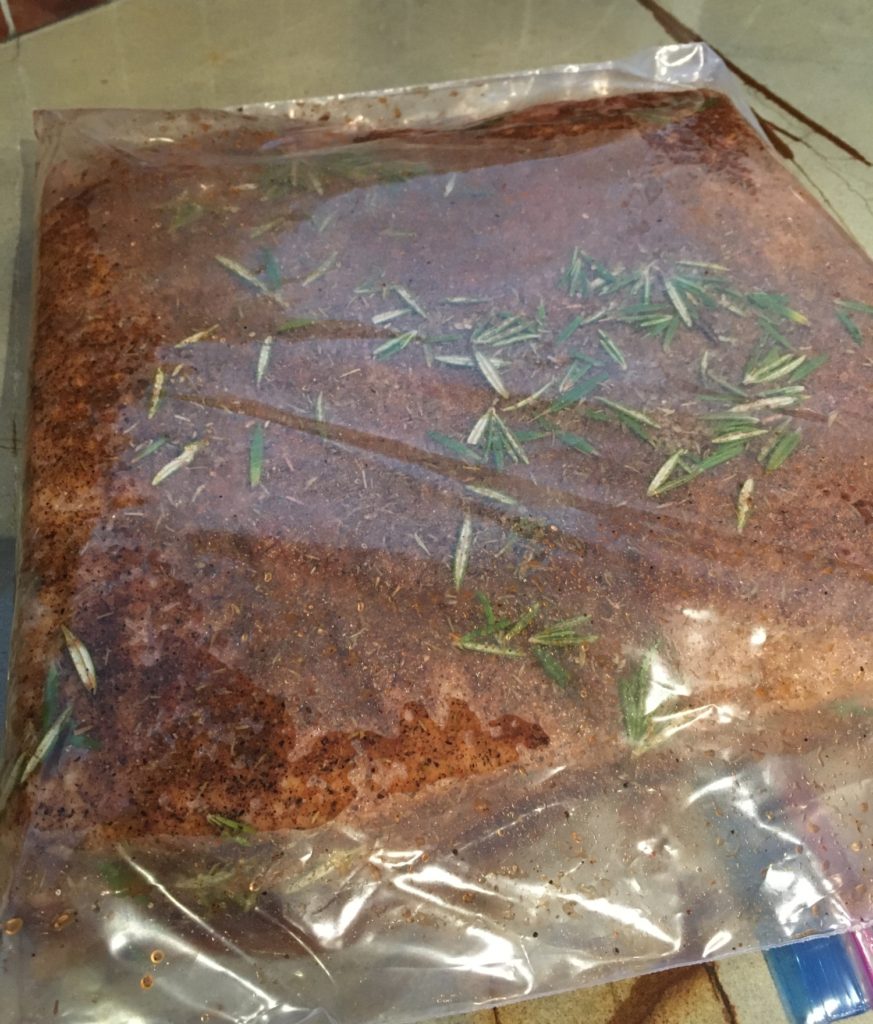 pork belly covered in curing salt in a plastic bag